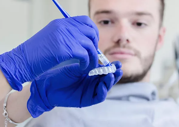 Man watching as whitening solution is applied to mold.